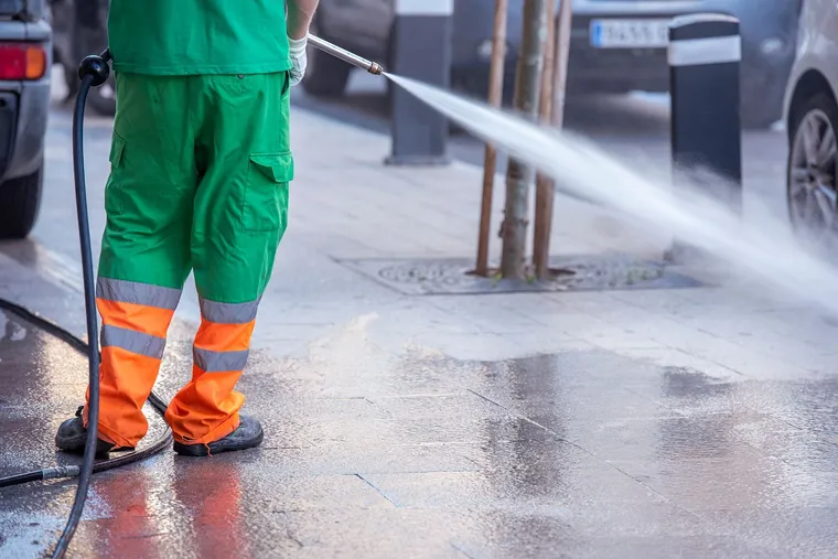 Worker pressure washing with a water pressure gun